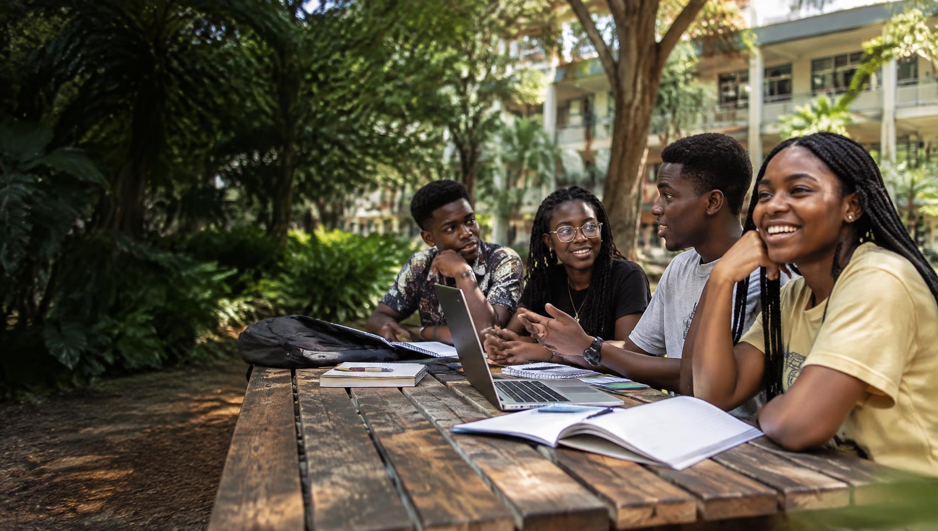 Young people sharing ideas around a table in a green campus setting